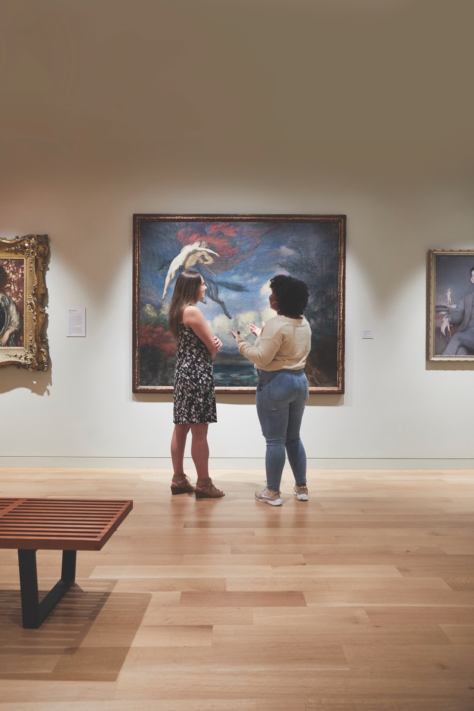 Two students studying a landscape painting in an exhibition gallery at the Danforth Art Museum.