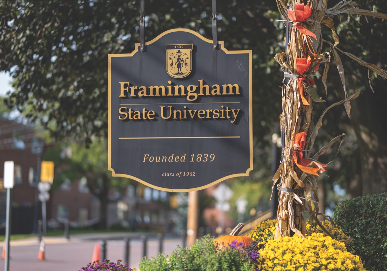 The Framingham State University campus sign, reading &ldquo;Founded 1839&rdquo;, with autumn mums and cornstalks at its base.