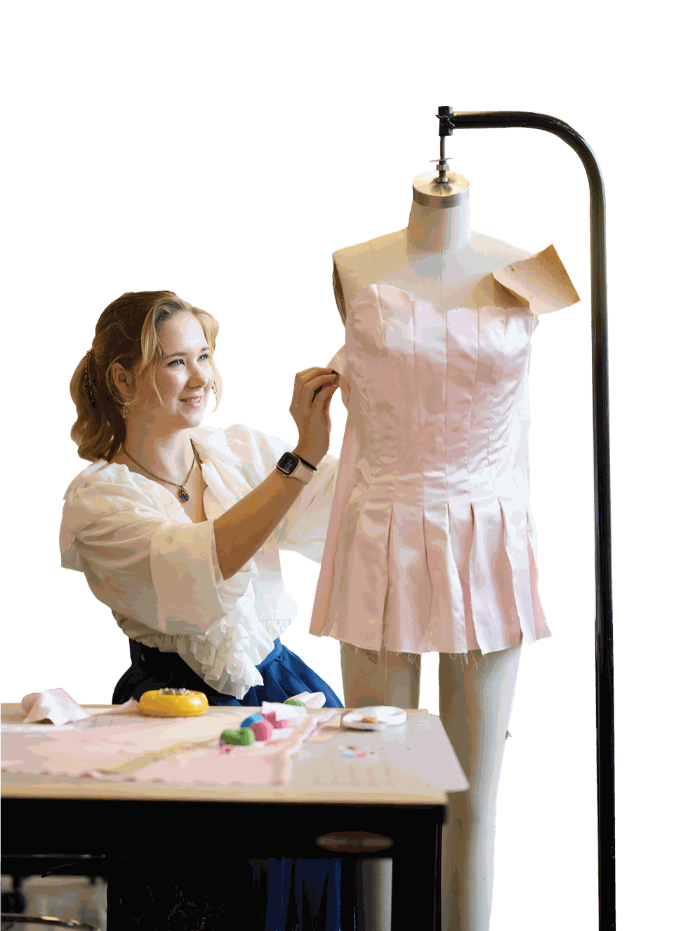 Aili Schiavoni, a Fashion Design major, adjusting a hand-sewn pale-pink dress on a dress form in the campus studio.