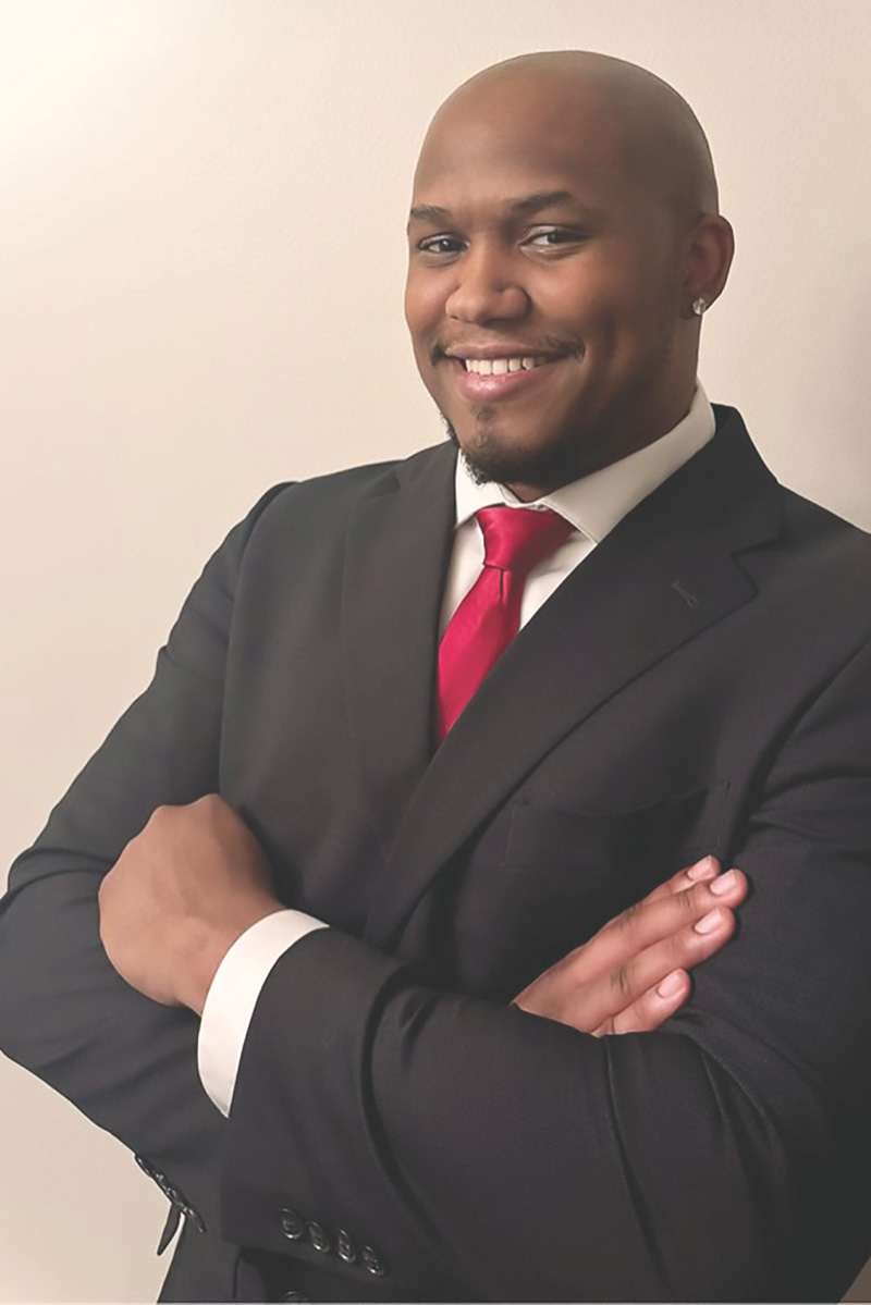 Gerald Fernandez, Class of 2025, an Accounting graduate now working as a Financial Analyst at Amazon HQ in Seattle, in a suit and red tie.