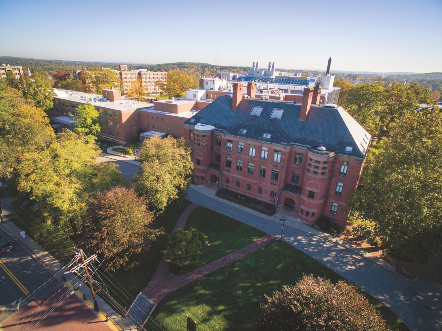 An aerial view of Framingham State&rsquo;s May Hall in autumn, brick facade framed by turning trees.